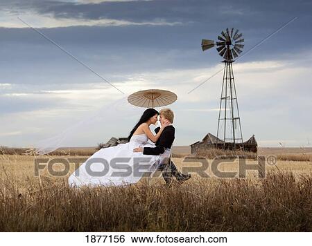 Stock Photograph - three hills, alberta, canada; a bride and groom in a farm field. Fotosearch