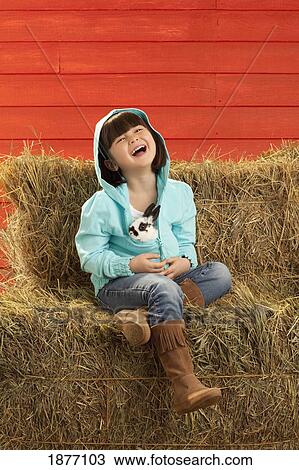 three hills, alberta, canada; a girl sitting on hay bales holding a bunny rabbit View Large Photo Image Stock Image - three hills, alberta, canada; a girl sitting on hay bales holding a bunny rabbit. Fotosearch