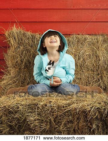 Stock Image - three hills, alberta, canada; a young girl holding a bunny rabbit. Fotosearch