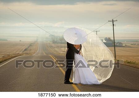 three hills, alberta, canada; bride and groom in an embrace standing on a road in rural alberta View Large Photo Image Stock Image - three hills, alberta, canada; bride and groom in an embrace standing on a road in rural alberta. Fotosearch