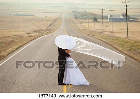 three hills, alberta, canada; bride and groom in an embrace standing on a road in rural alberta View Large Photo Image Stock Photo - three hills, alberta, canada; bride and groom in an embrace standing on a road in rural alberta. Fotosearch