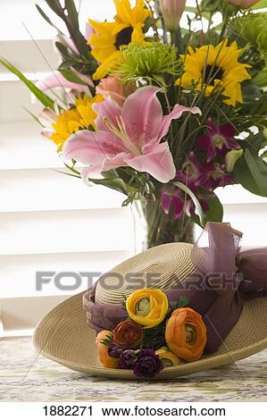 vase of flowers and a straw bonnet with flowers on a table top View Large Photo Image Stock Image - vase of flowers and a straw bonnet with flowers on a table top. Fotosearch