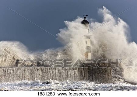 Stock Image - waves crashing up against a lighthouse; seaham, teesside, england. Fotosearch