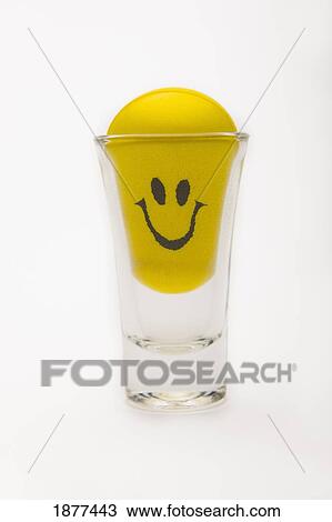 Stock Image - yellow happy face in a shot glass; edmonton, alberta, canada. Fotosearch
