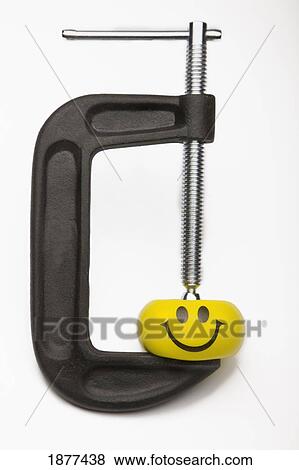Stock Photo - yellow happy face squeezed by a clamp; edmonton, alberta, canada. Fotosearch