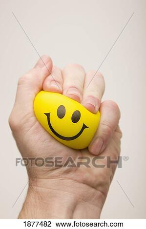 yellow happy face squeezed by a hand; edmonton, alberta, canada View Large Photo Image Stock Image - yellow happy face squeezed by a hand; edmonton, alberta, canada. Fotosearch