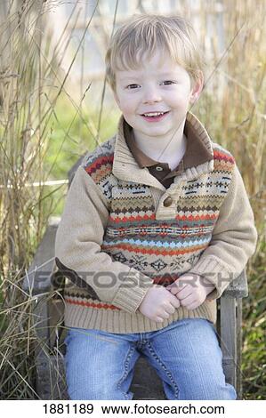Stock Photo - young boy sitting on a chair outdoors; portland, oregon, united states of america. Fotosearch