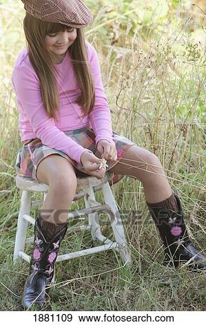 young girl sitting on a stool wearing a hat and cowboy boots; troutdale, oregon, united states of america View Large Photo Image Stock Photo - young girl sitting on a stool wearing a hat and cowboy boots; troutdale, oregon, united states of america. Fotosearch