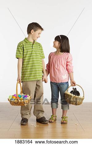 A Boy And Girl Holding Baskets With A Rabbit And Colorful Easter Eggs In Them View Large Photo Image Picture - A Boy And Girl Holding Baskets With A Rabbit And Colorful Easter Eggs In Them. Fotosearch