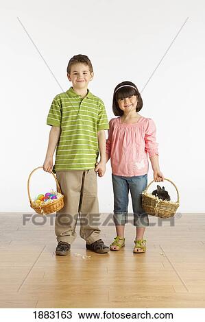 A Boy And Girl Holding Baskets With A Rabbit And Colorful Easter Eggs In Them View Large Photo Image Stock Image - A Boy And Girl Holding Baskets With A Rabbit And Colorful Easter Eggs In Them. Fotosearch