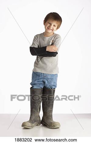 Stock Image - A Boy Wearing Oversized Rubber Boots. Fotosearch