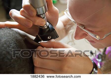 Stock Photograph - A Doctor Checks The Ears Of A Patient; Manica, Mozambique, Africa. Fotosearch