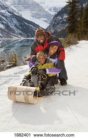 A Family On A Toboggan In The Snow With Mountains In The Background; Lake Louise, Alberta, Canada View Large Photo Image Stock Image - A Family On A Toboggan In The Snow With Mountains In The Background; Lake Louise, Alberta, Canada. Fotosearch