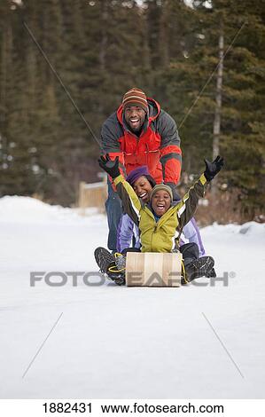 A Family Playing With A Toboggan In The Snow; Lake Louise, Alberta, Canada View Large Photo Image Stock Image - A Family Playing With A Toboggan In The Snow; Lake Louise, Alberta, Canada. Fotosearch