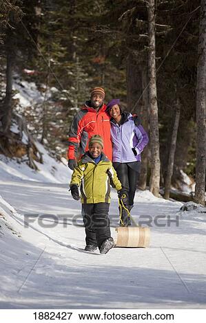 Stock Photo - A Family Walking In The Snow With A Toboggan; Lake Louise, Alberta, Canada. Fotosearch
