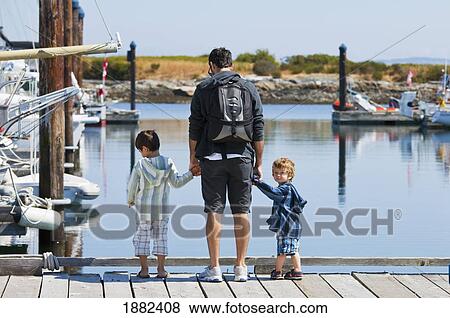 A Father With Two Sons Standing On A Dock Looking Into The Water; Langley, British Columbia, Canada View Large Photo Image Stock Photo - A Father With Two Sons Standing On A Dock Looking Into The Water; Langley, British Columbia, Canada. Fotosearch