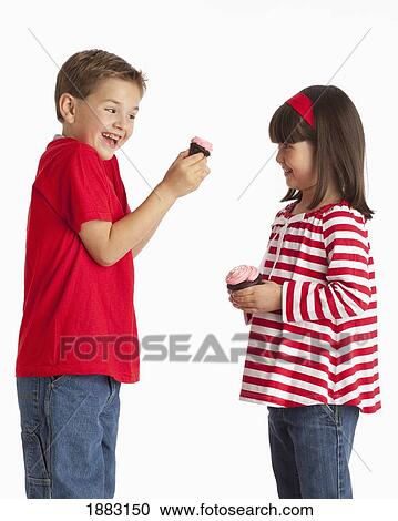 Stock Image - A Girl And Boy Holding Chocolate Cupcakes. Fotosearch