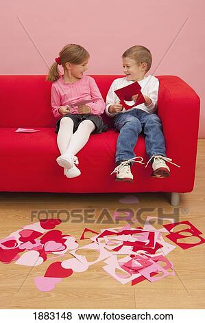 A Girl And Boy Sit On A Couch Cutting Out Hearts View Large Photo Image Stock Photo - A Girl And Boy Sit On A Couch Cutting Out Hearts. Fotosearch