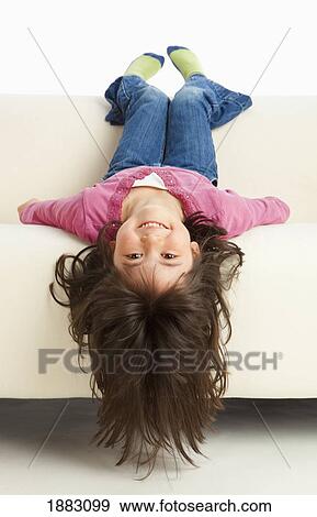 Stock Photo - A Girl Hanging Upside Down From The Couch. Fotosearch