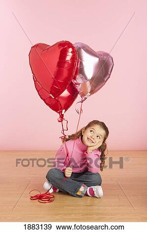 Stock Photo - A Girl Holding Heart Shaped Balloons. Fotosearch
