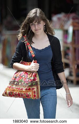 Stock Image - A Girl Walks Through A Thai Market; Chiang Mai, Thailand. Fotosearch