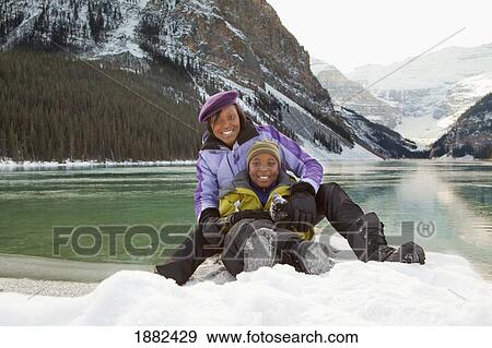 A Mother And Son Sitting Together In The Snow; Lake Louise, Alberta, Canada View Large Photo Image Stock Photo - A Mother And Son Sitting Together In The Snow; Lake Louise, Alberta, Canada. Fotosearch