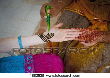 Stock Photography - A Woman Doing Henna Painting On Another Woman's Arm; Sathyamangalam, Tamil Nadu, India. Fotosearch