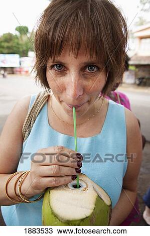 Stock Image - A Woman Drinking Out Of A Coconut With A Straw; Mysore, Karnataka, India. Fotosearch