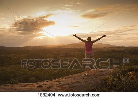 Picture - A Woman With Her Arms Raised To The Sky At Sunset; Manica, Mozambique, Africa. Fotosearch