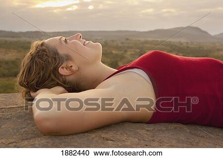 A Young Woman Lays On Her Back On A Rock With The African Landscape In The Background; Manica, Mozambique, Africa View Large Photo Image Stock Image - A Young Woman Lays On Her Back On A Rock With The African Landscape In The Background; Manica, Mozambique, Africa. Fotosearch