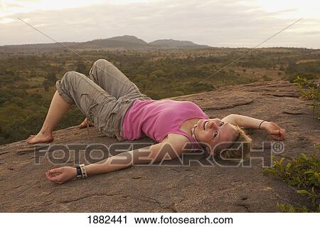 A Young Woman Lays On Her Back On A Rock With The African Landscape In The Background; Manica, Mozambique, Africa View Large Photo Image Stock Image - A Young Woman Lays On Her Back On A Rock With The African Landscape In The Background; Manica, Mozambique, Africa. Fotosearch