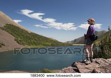 Female Hiker Overlooking A Lake While Standing On A Rock Cliff; Waterton, Alberta, Canada View Large Photo Image Stock Image - Female Hiker Overlooking A Lake While Standing On A Rock Cliff; Waterton, Alberta, Canada. Fotosearch