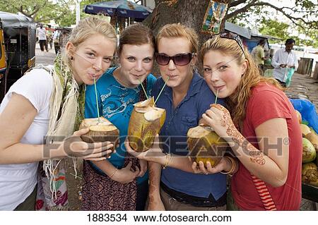 Picture - Four Girls Drinking Out Of Coconuts With Straws; Mysore, Karnataka, India. Fotosearch