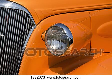 Stock Image - Orange Painted Vintage Car's Headlight And Front Grill; Port Colborne, Ontario, Canada. Fotosearch
