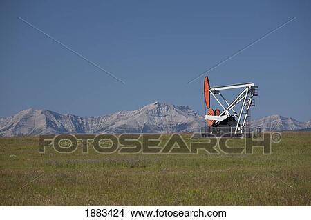 Pumpjack With Mountains And Blue Sky In The Background; Alberta, Canada View Large Photo Image Picture - Pumpjack With Mountains And Blue Sky In The Background; Alberta, Canada. Fotosearch