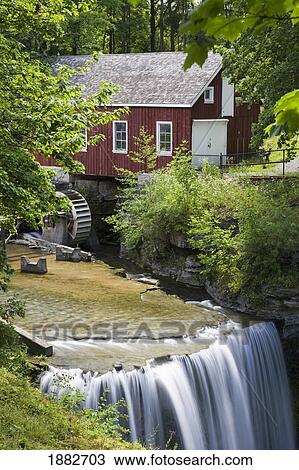 Stock Image - Red Barn With A Mill Wheel And Waterfall; Thorold, Ontario, Canada. Fotosearch