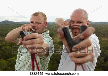 Two Men Pointing Slingshots At The Camera; Manica, Mozambique, Africa View Large Photo Image Stock Photography - Two Men Pointing Slingshots At The Camera; Manica, Mozambique, Africa. Fotosearch