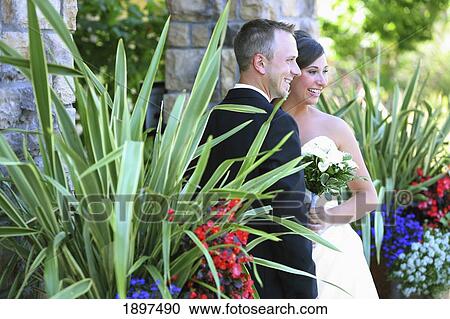 Stock Image - a bride and groom posing for pictures in a garden area; troutdale, oregon, united states of america. Fotosearch
