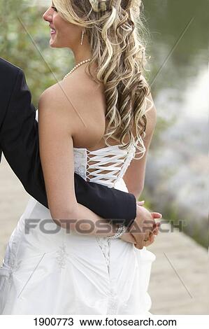 a bride holds her groom's hand behind her back; edmonton, alberta, canada View Large Photo Image Stock Image - a bride holds her groom's hand behind her back; edmonton, alberta, canada. Fotosearch