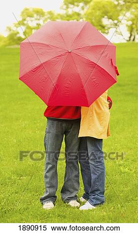 Stock Photography - a couple hiding behind an umbrella; wilmar, minnesota, united states of america. Fotosearch