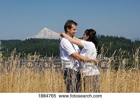 Stock Photography - a couple in an embrace in a wheat field; portland, oregon, united states of america. Fotosearch