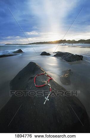a cross and rosary beads laying on a rock at flat rock; bellina, new south wales, australia View Large Photo Image Stock Photograph - a cross and rosary beads laying on a rock at flat rock; bellina, new south wales, australia. Fotosearch