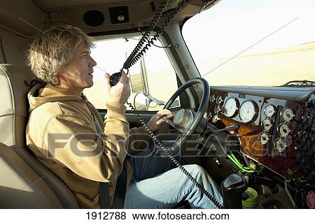 Stock Photo - a driver talking into his radio in a truck; three hills, alberta, canada. Fotosearch