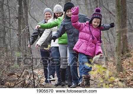 Stock Image - a family takes a walk and balances on a log in the woods; grimsby, ontario, canada. Fotosearch
