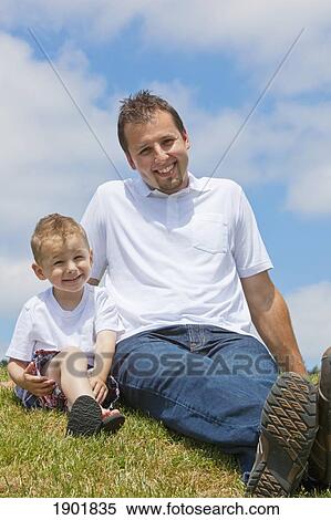 Stock Photography - a father and son sitting on the grass; portland, oregon, united states of america. Fotosearch