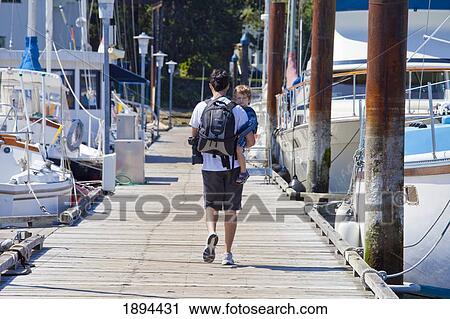 a father holding his young son as he walks down a pier in a marina; victoria, british columbia, canada View Large Photo Image Stock Image - a father holding his young son as he walks down a pier in a marina; victoria, british columbia, canada. Fotosearch