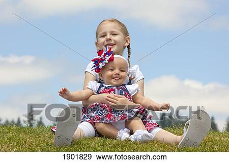 a girl holding her baby sister on the grass; portland, oregon, united states of america View Large Photo Image Stock Photo - a girl holding her baby sister on the grass; portland, oregon, united states of america. Fotosearch