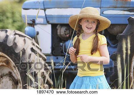 a girl wearing a large straw hat standing in front of a tractor; troutdale, oregon, united states of america View Large Photo Image Stock Image - a girl wearing a large straw hat standing in front of a tractor; troutdale, oregon, united states of america. Fotosearch