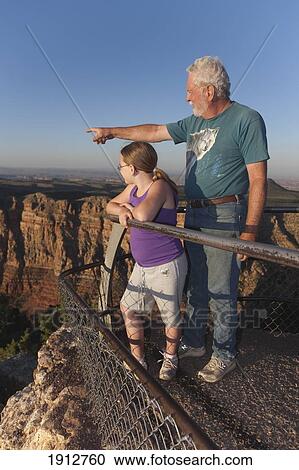 Stock Image - a grandfather points out features of the grand canyon to his granddaughter; arizona, united states of america. Fotosearch