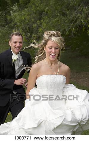 a groom playfully chases his bride through a park; st. albert, alberta, canada View Large Photo Image Stock Image - a groom playfully chases his bride through a park; st. albert, alberta, canada. Fotosearch